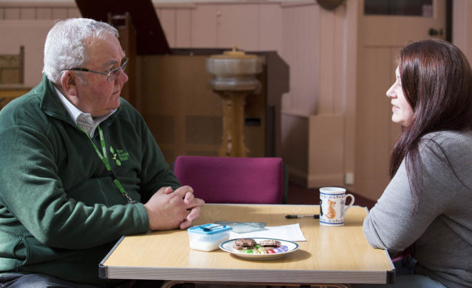 voluteer chatting to client over tea and biscuits
